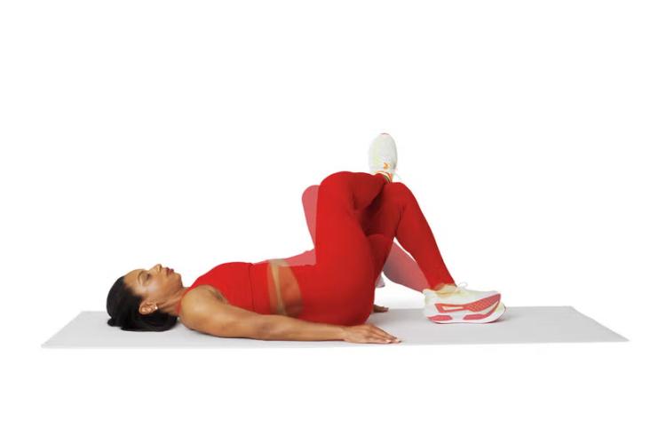 Een vrouw ligt op haar rug op een yogamatje en voert de Figure Four to Twist uit